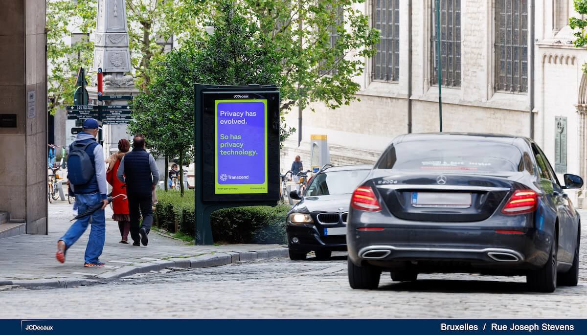 A photograph of a street scene in Brussels, showing a Transcend advertisement on a digital billboard that reads 'Privacy has evolved. So has privacy technology.' Cars and pedestrians are visible in the background.
