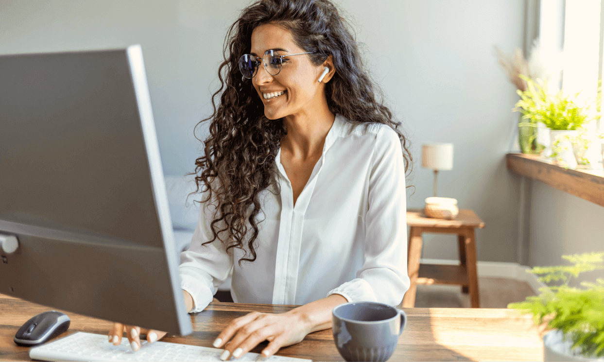 Professional woman smiling while working at desk with headphones in