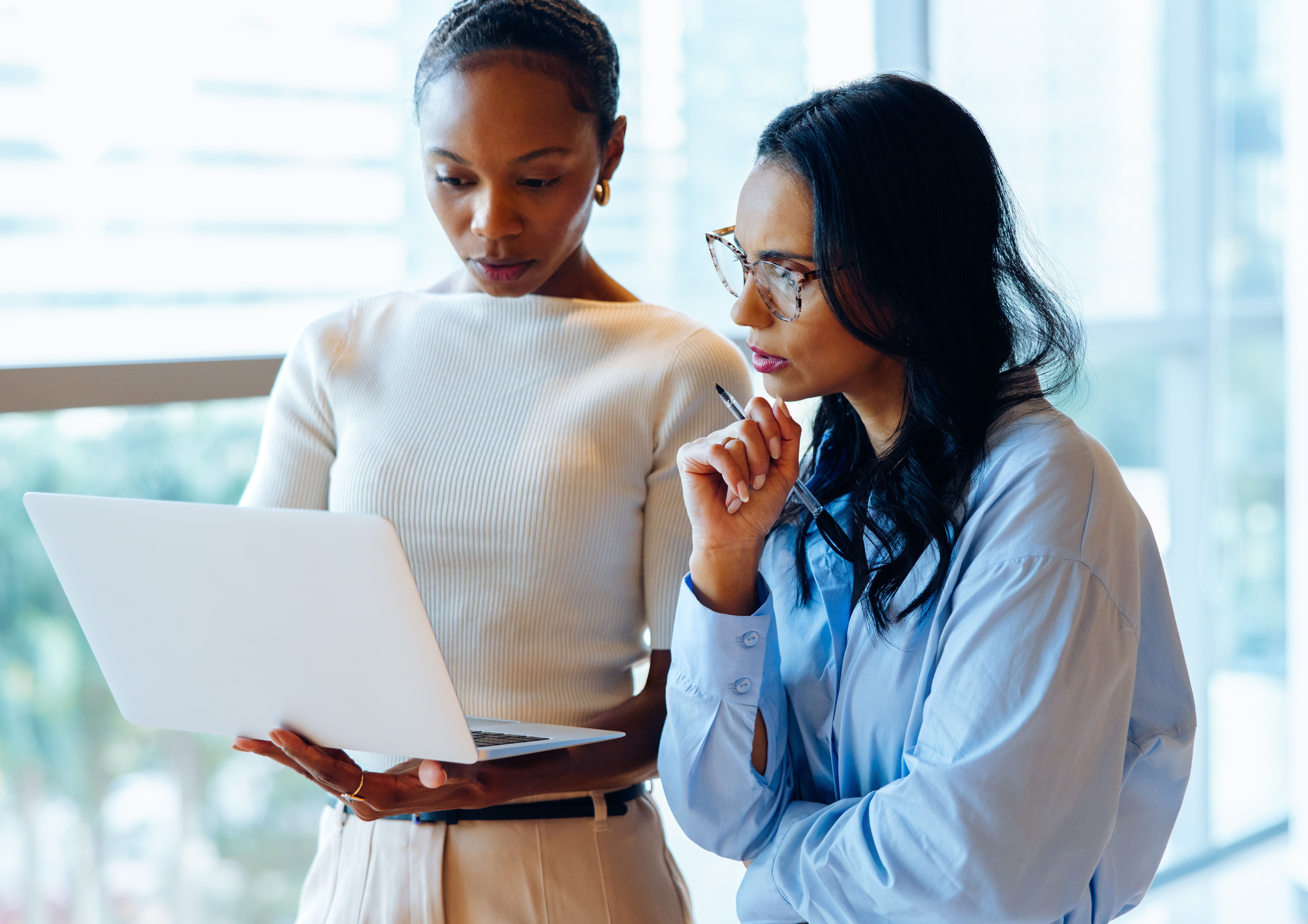 Two women collaborating while looking at a laptop.