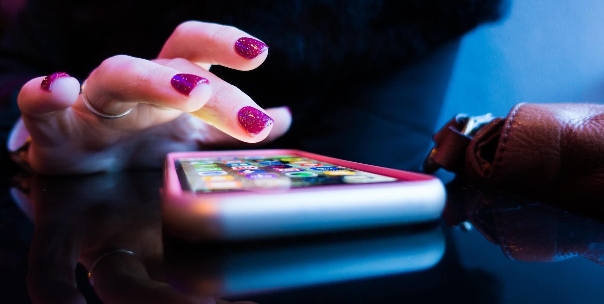 Women's bright nail polished fingers using an iphone in an extreme close up