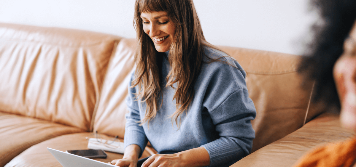 Woman working on laptop from couch smiling