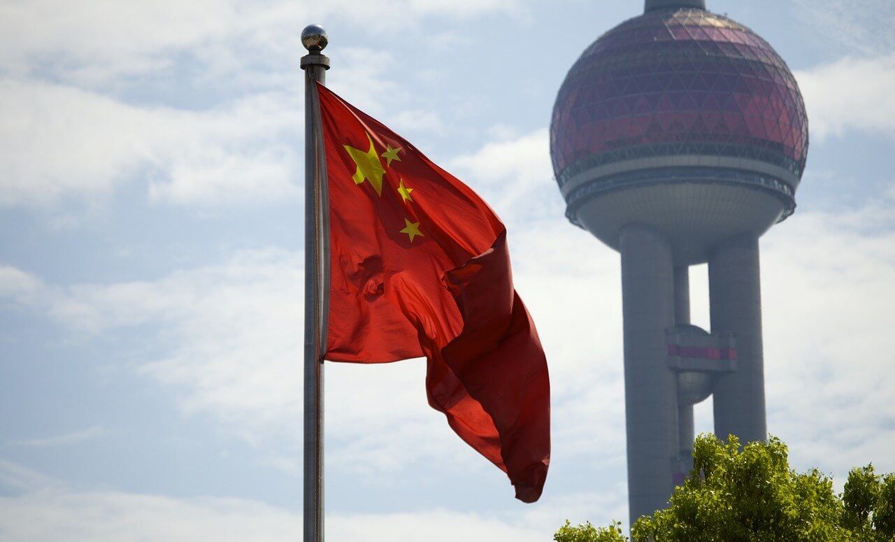 Flag of china waving in front of large tower