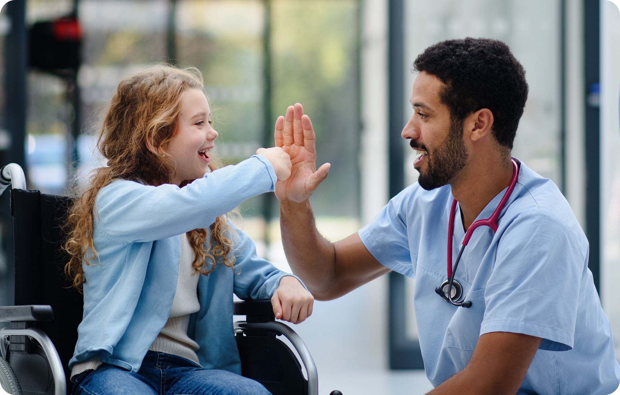 Smiling girl in a wheelchair high-fiving a male medical professional.