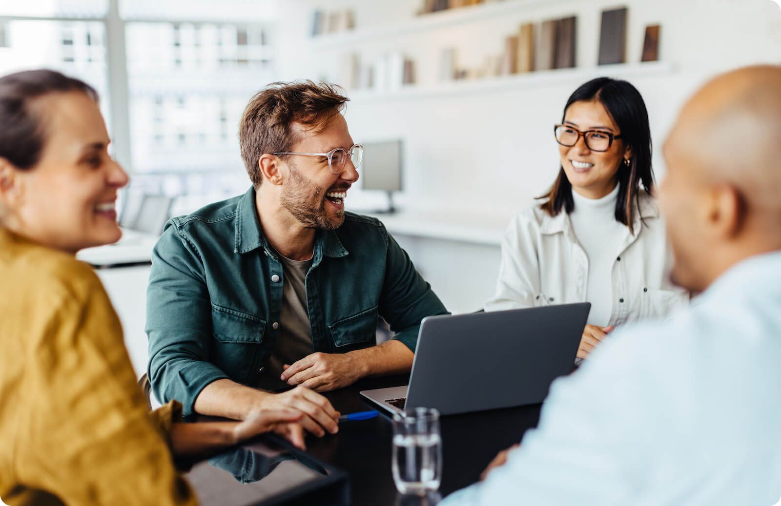 Group of professionals smiling and laughing around modern office setting