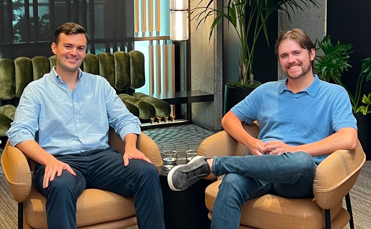 Two smiling men sitting in armchairs in a modern office lounge.