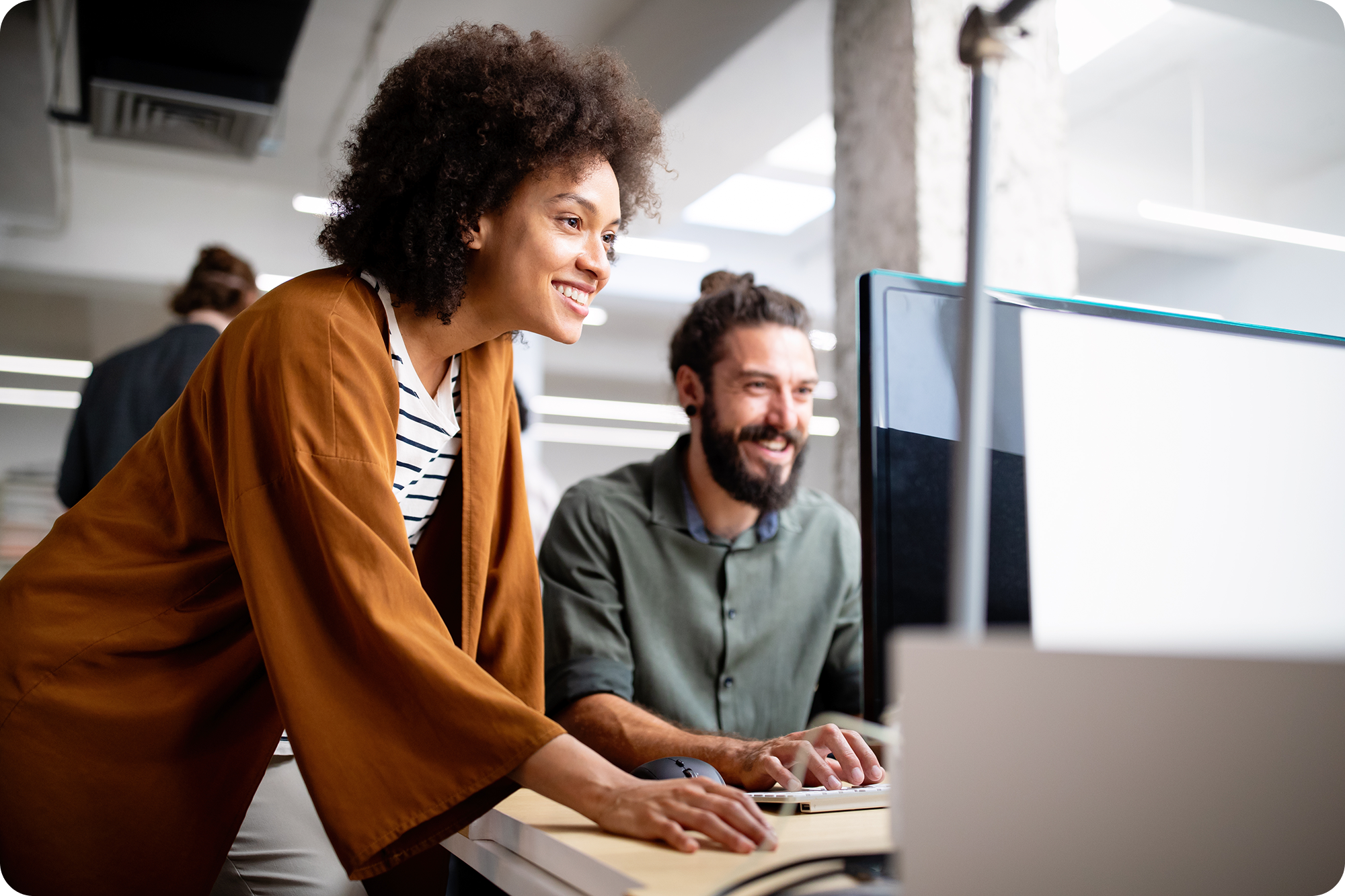 Two professionals smiling as they look at a computer