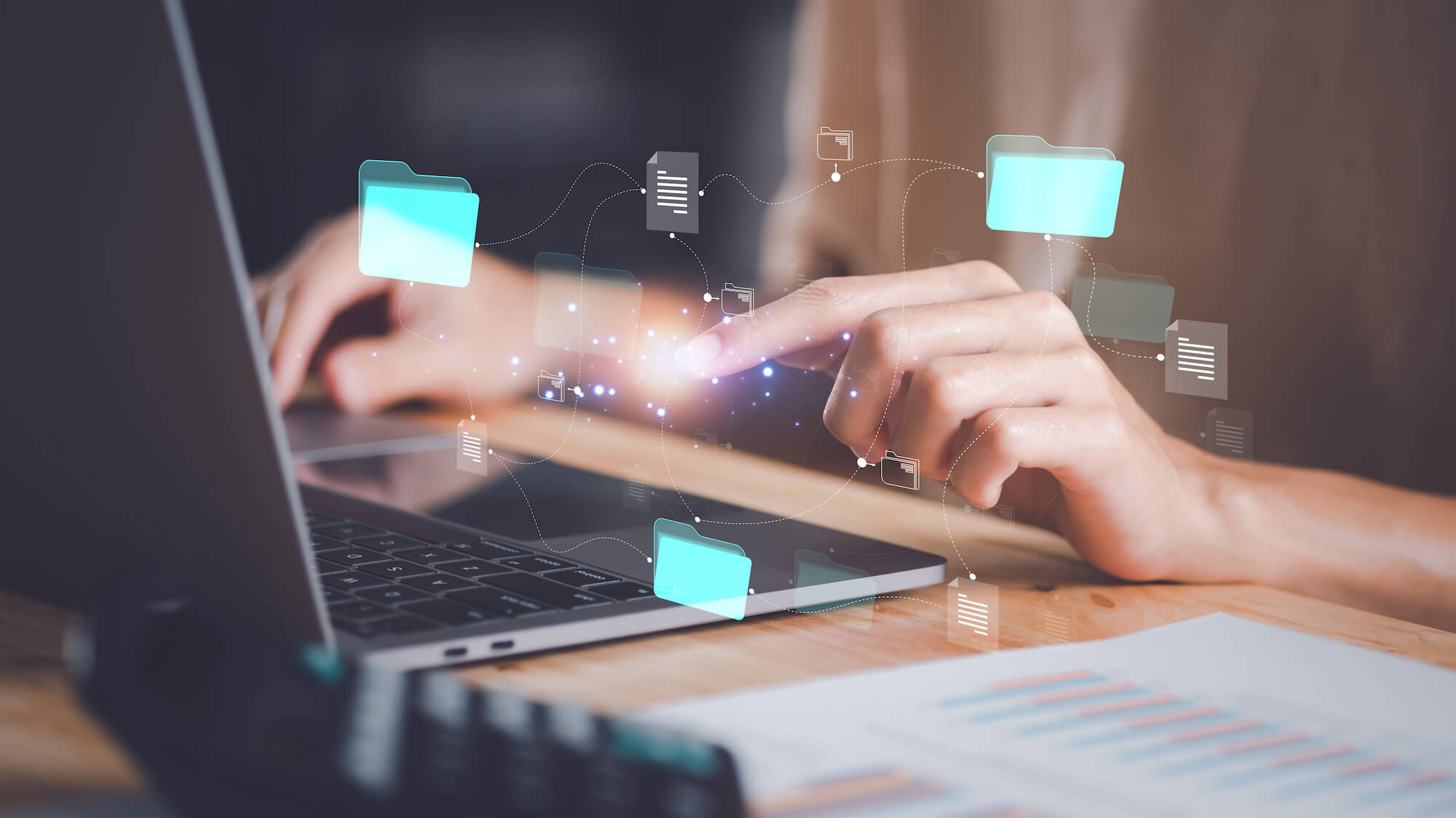 Hands hovering over laptop keyboard with stylized images of files and the connections between them