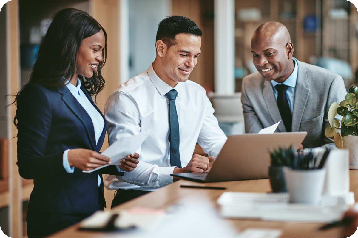 Three legal professionals smiling and looking at a laptop computer
