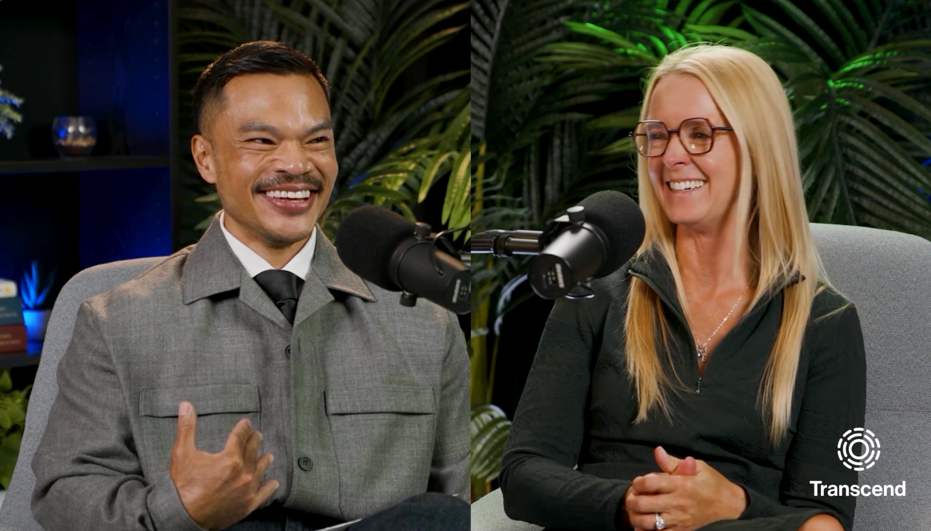 A man and a woman are seated next to each other, smiling and speaking into microphones. Lush greenery is in the background, and a small logo reading "Transcend" appears in the bottom right corner.