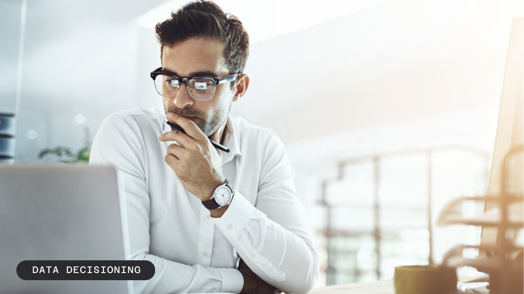 A man in glasses looking thoughtfully at a laptop screen. Text: DATA DECISIONING.