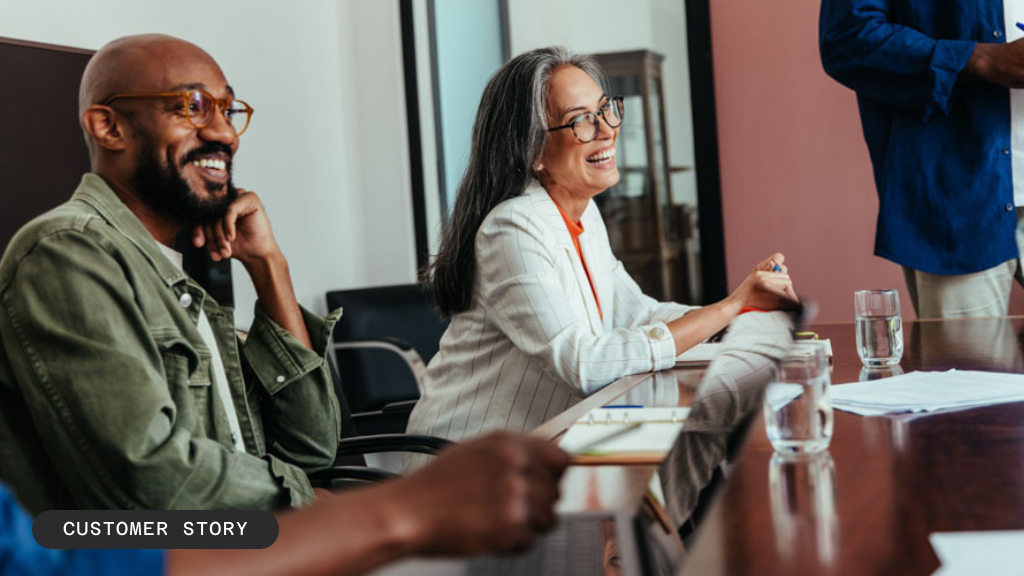 A smiling Black man and older white woman sit at a meeting table. Text: CASE STUDY / CUSTOMER STORY.