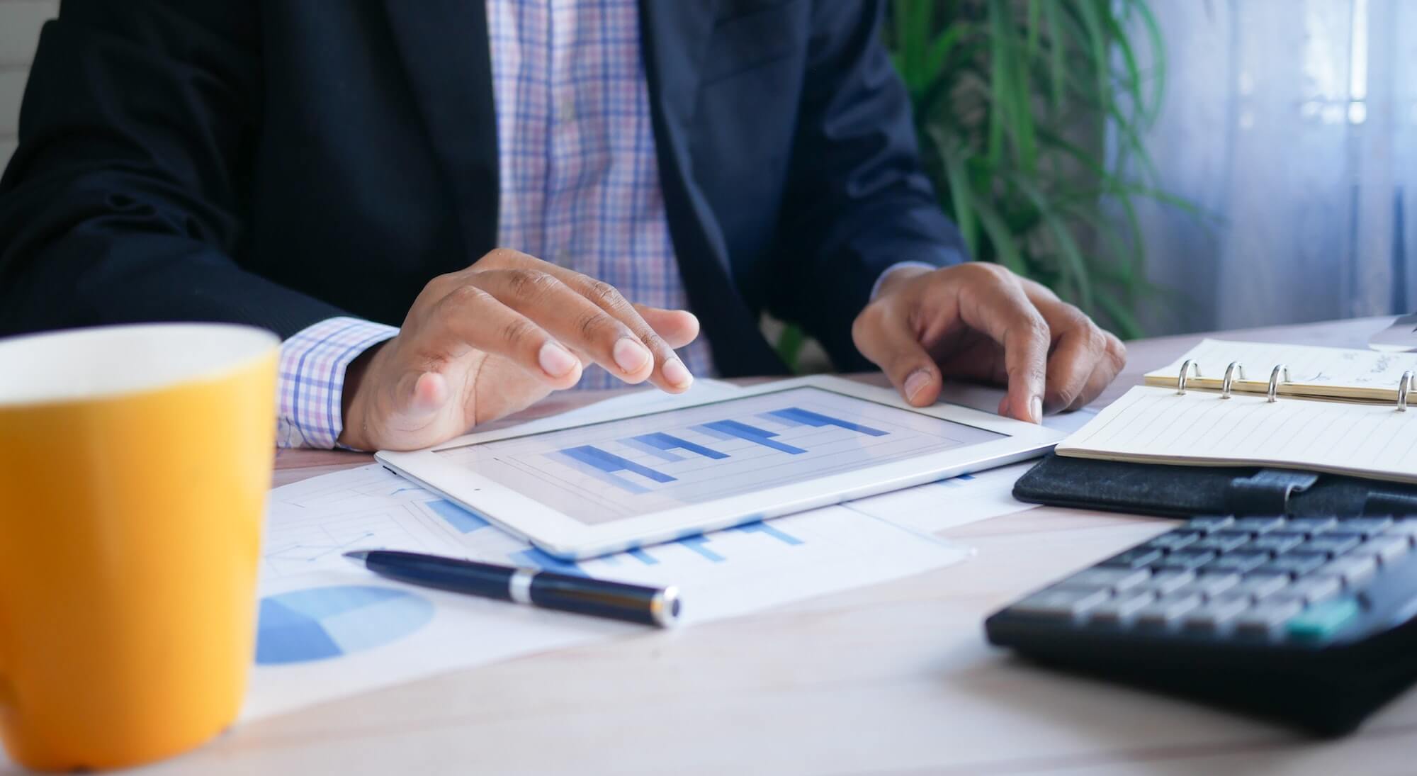 Professional using tablet on desk to view graphs