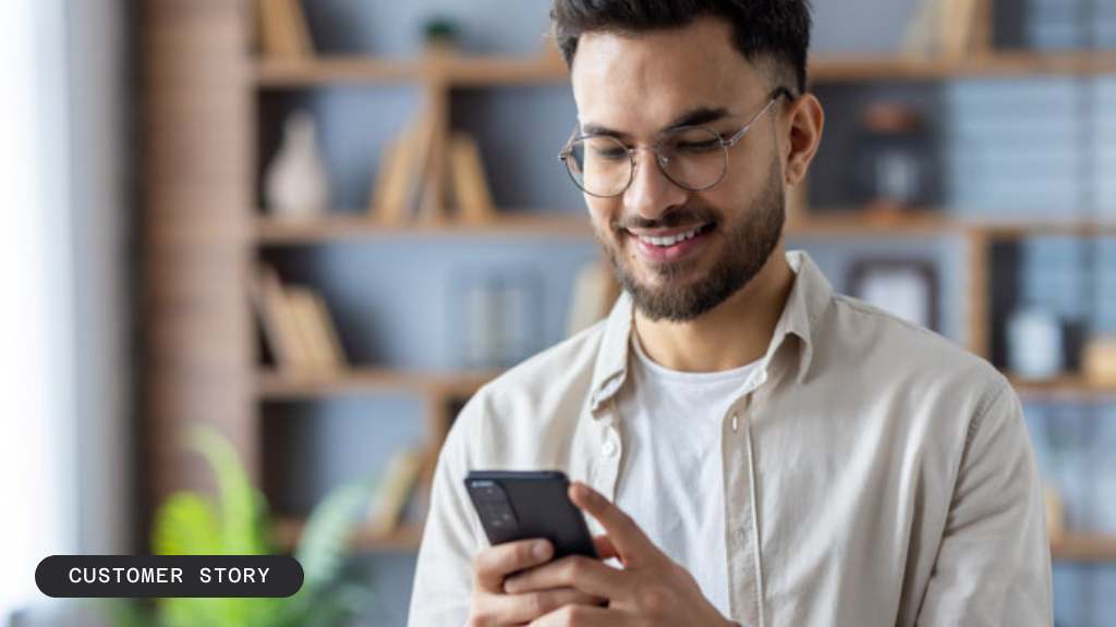 Smiling man with glasses looking at his smartphone.