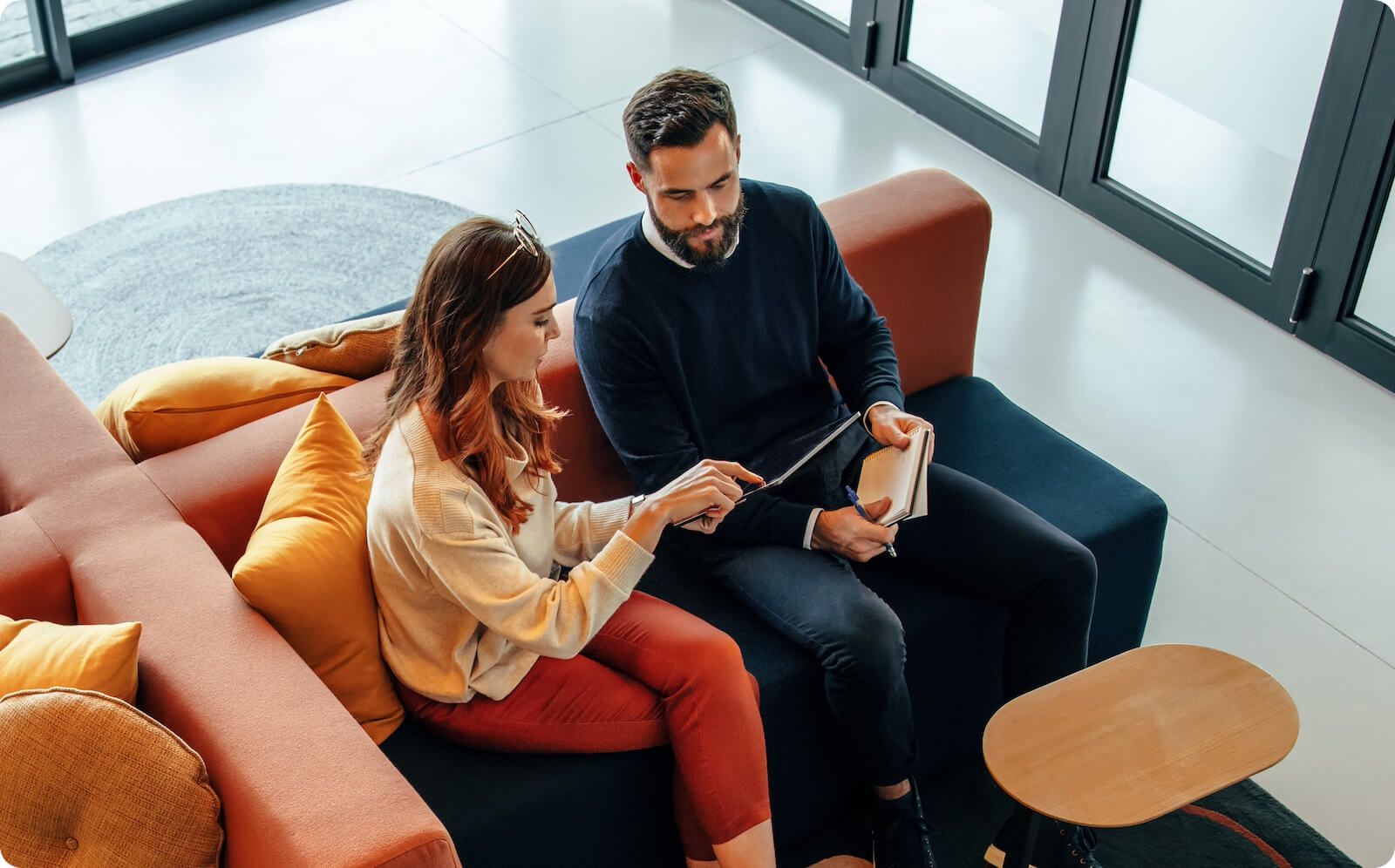 Man and woman sitting on couch in modern office setting looking at data within a consent management platform