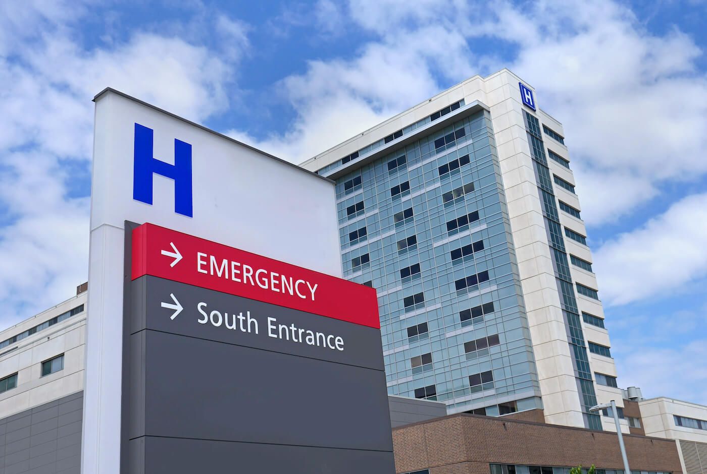 An outside view of hospital building in front of the emergency room direction sign