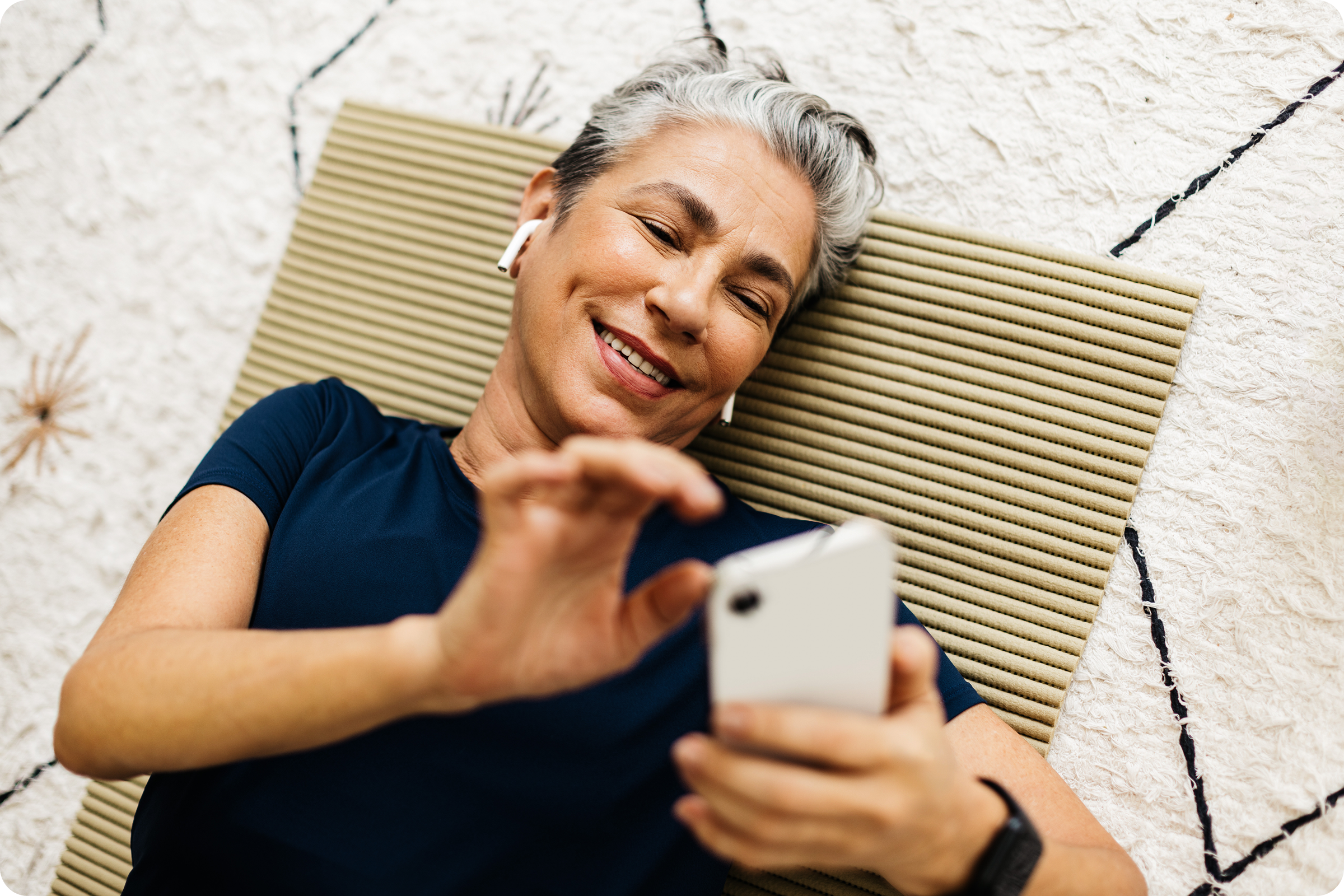 Person with gray hair and first generation apple airpods smiling at phone