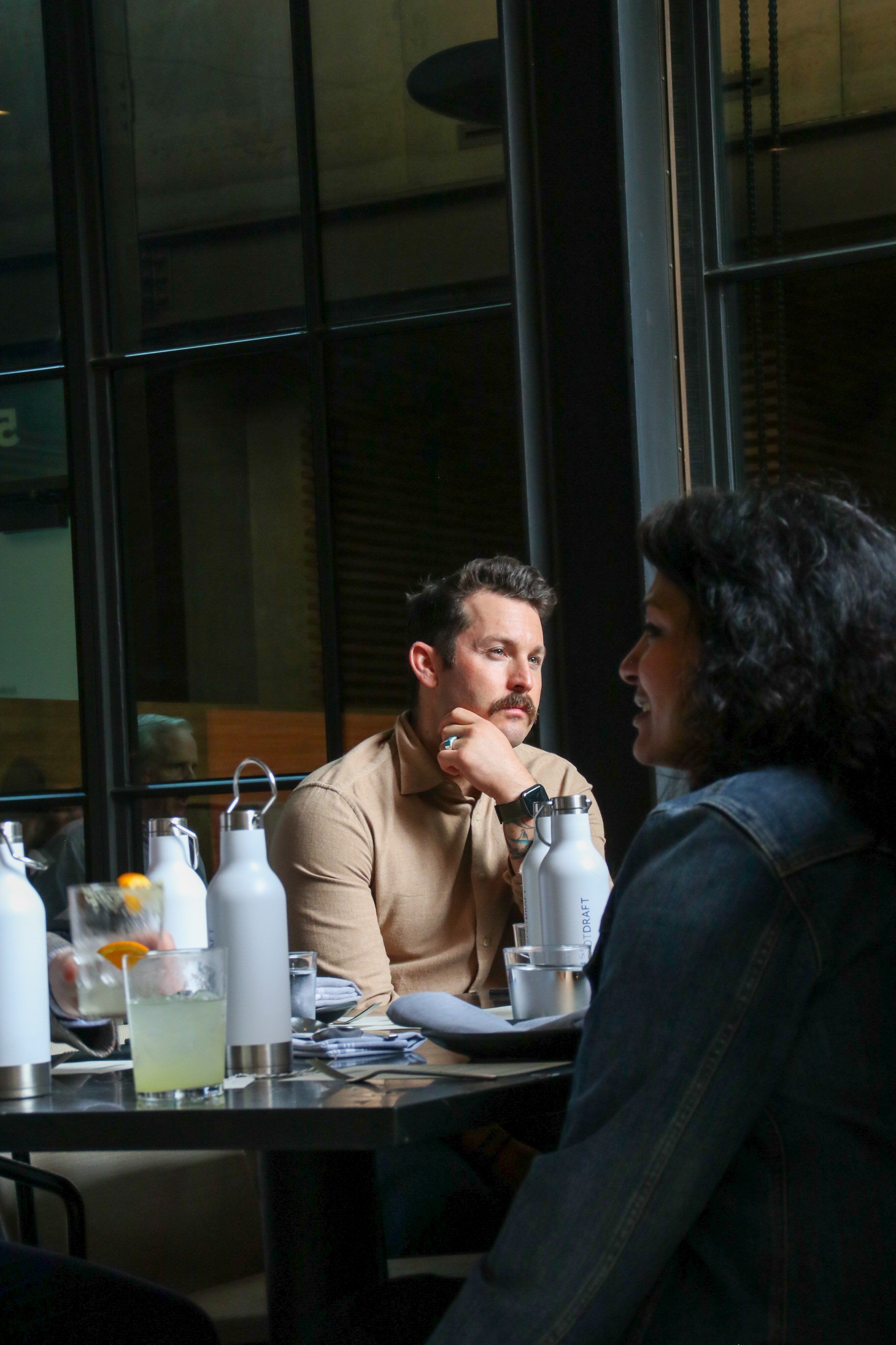 A man at a restaurant table pondering conversation