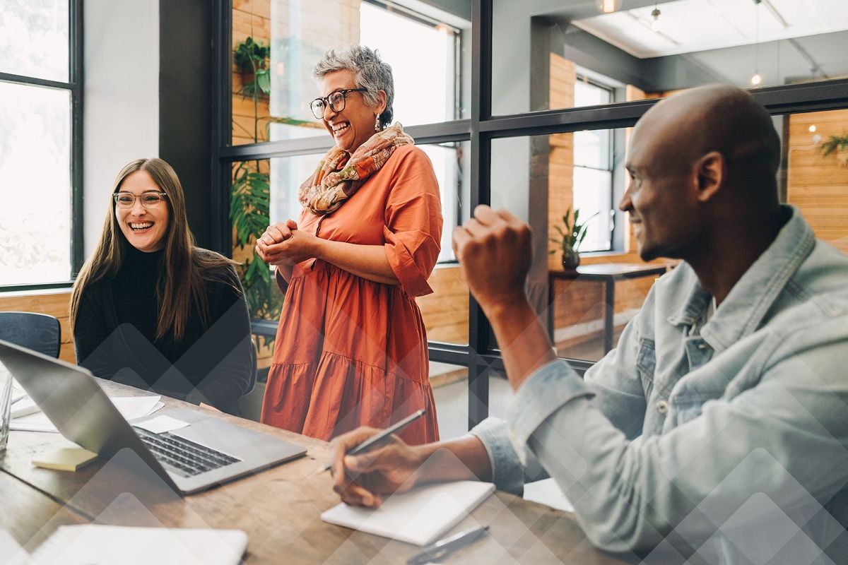 A diverse group of three professionals laughing and talking at a conference table.