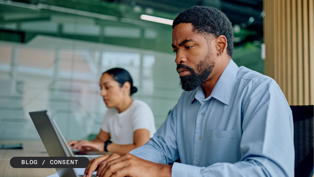 A man and a woman work on laptops in an office, with a "BLOG / CONSENT" banner.
