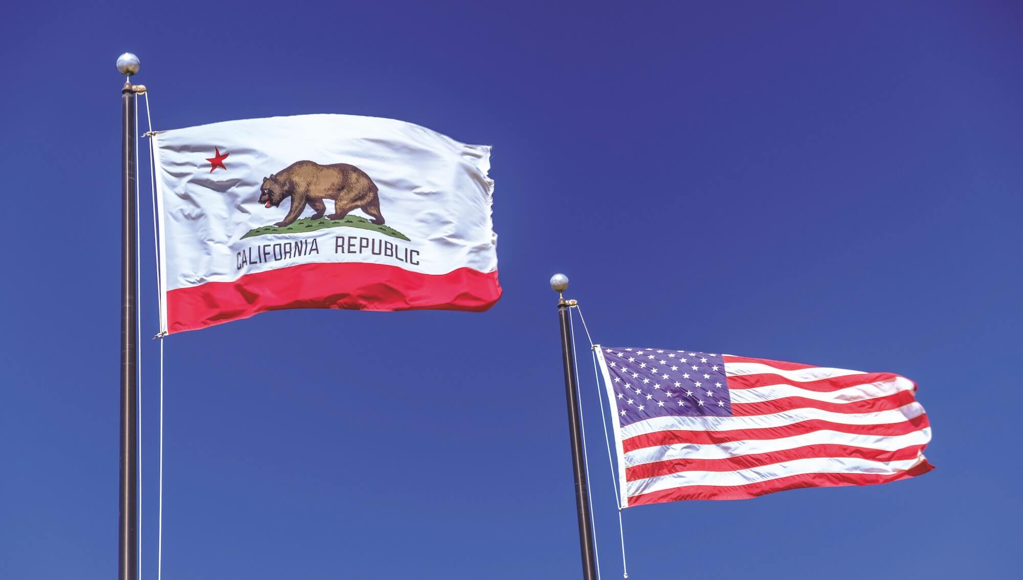 The california state flag and US flag waving in front of blue background
