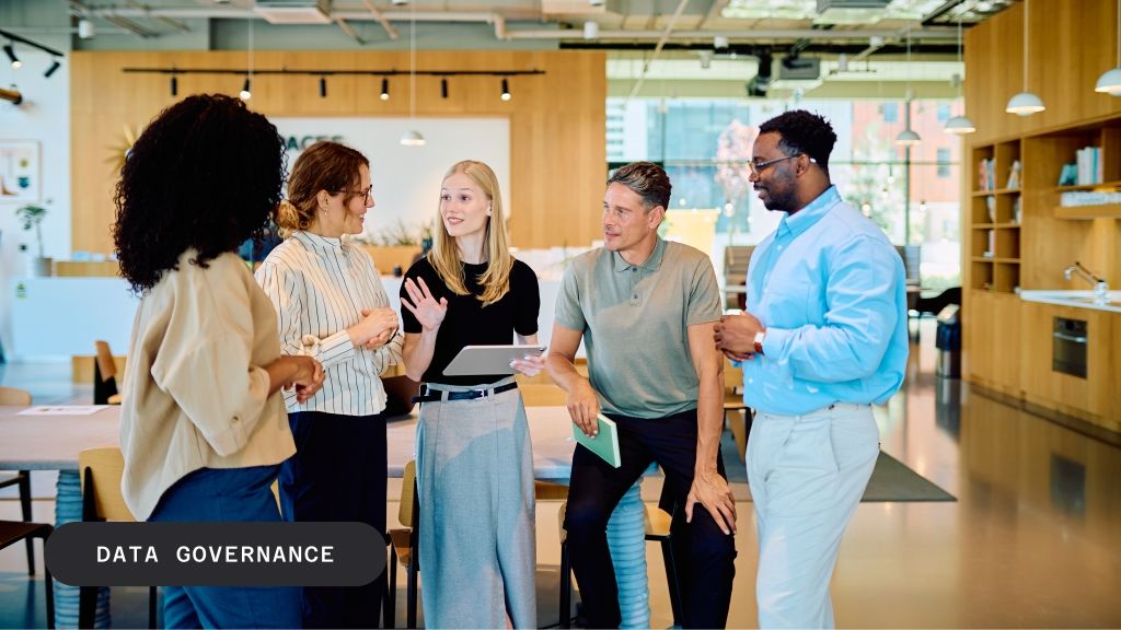 Five diverse professionals discuss in a modern office, with "DATA GOVERNANCE" text overlay.