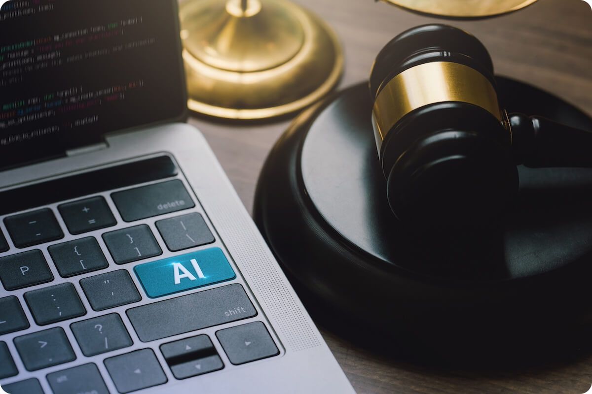 Closeup of laptop and judges gavel with the enter key replaced by big letters AI