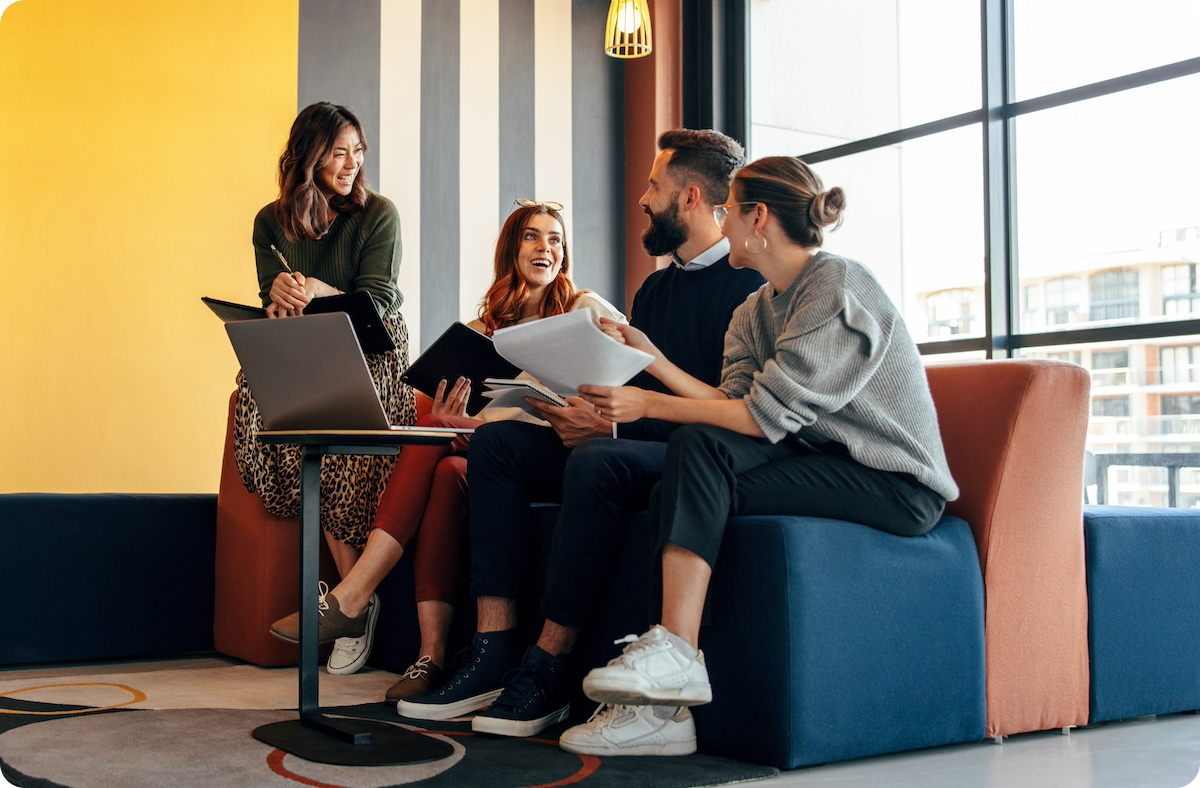Group of young professionals sitting on an office couch laughing