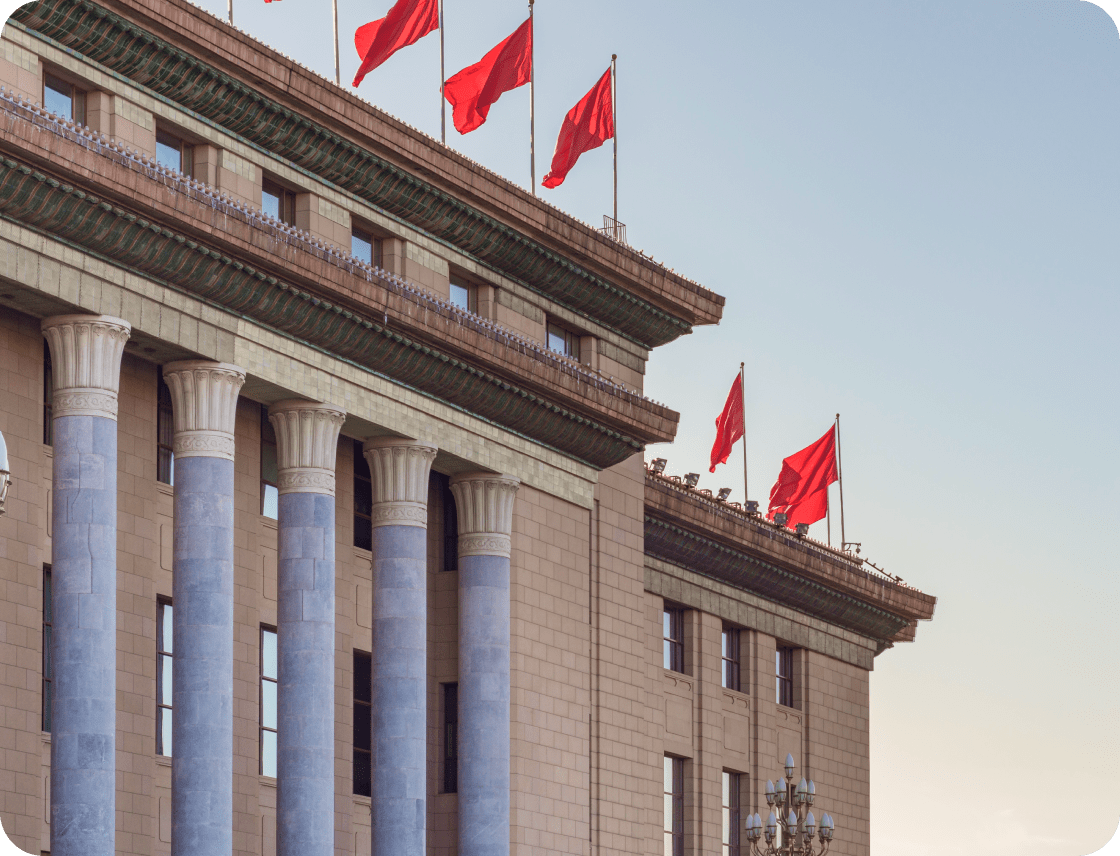 State building with Chinese flags waving in front of blue sky