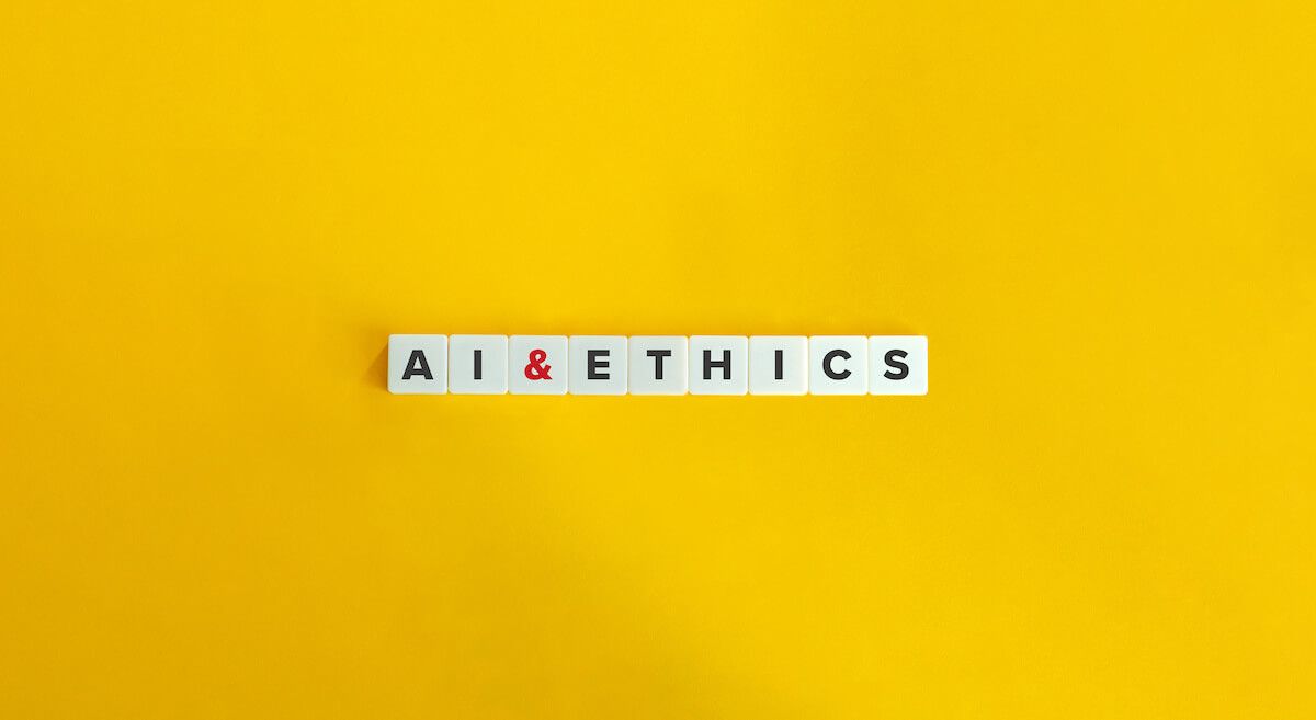 Scrabble tiles spelling out AI and Ethics in front of yellow background