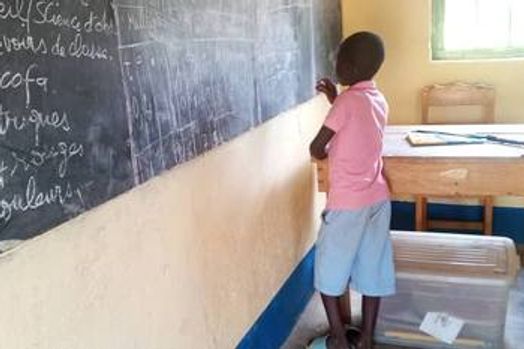 Un élève écrit au tableau noir dans une salle de classe.