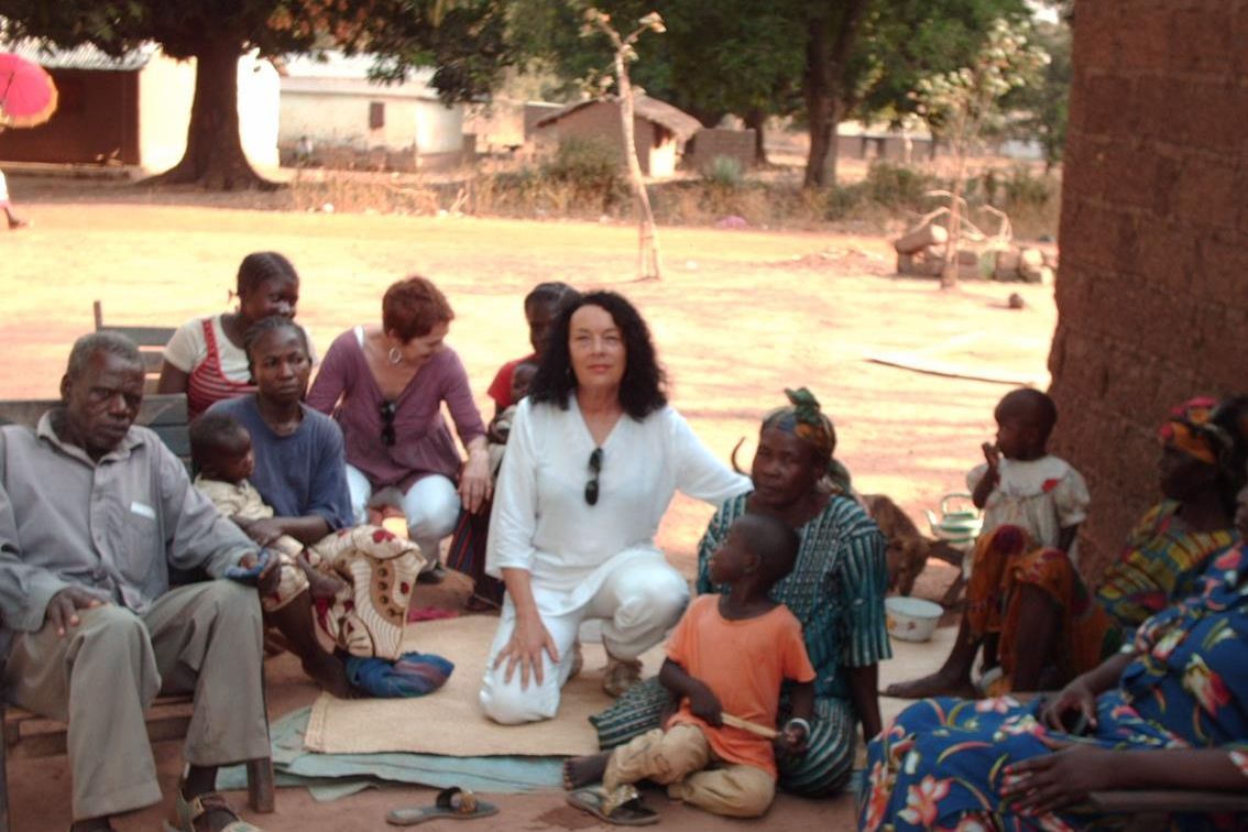 Catherine Parisel, vêtue de blanc, assise sur une natte parmi des enfants et des familles centrafricaines.