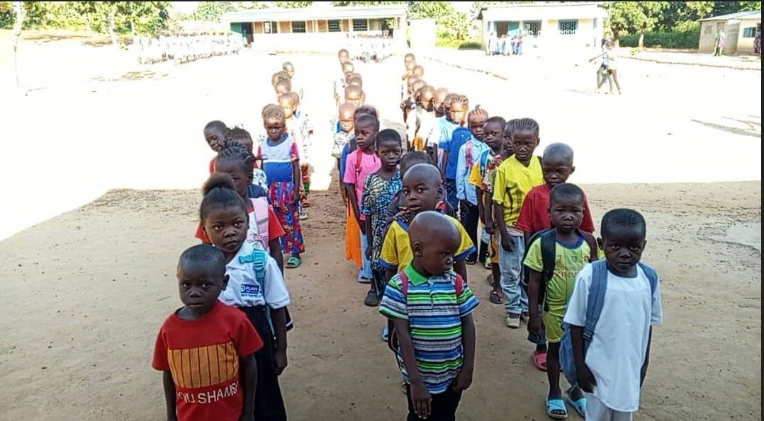 Les élèves de CP, en rang dans la cour de l’école, regardent l’objectif.