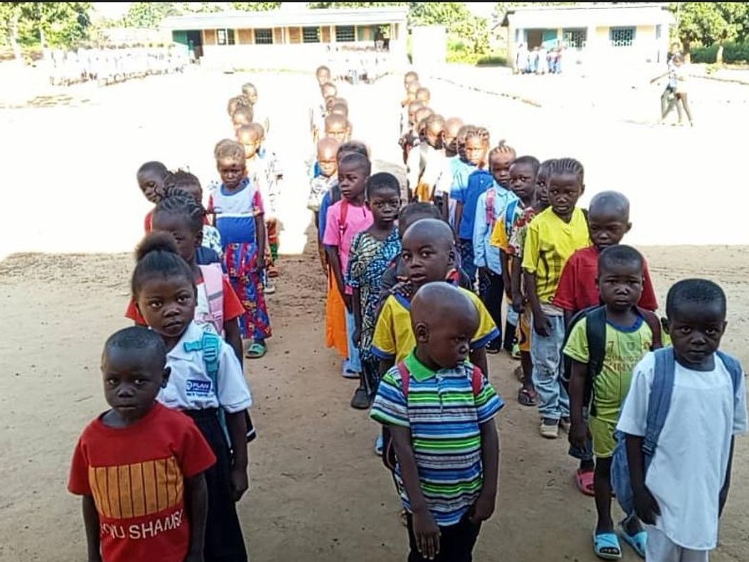 Les élèves de CP, en rang dans la cour de l’école, regardent l’objectif.