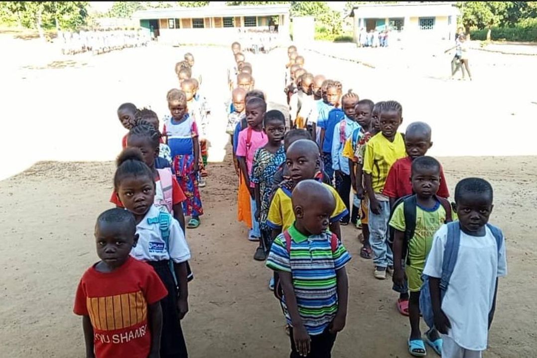 Les élèves de CP, en rang dans la cour de l’école, regardent l’objectif.