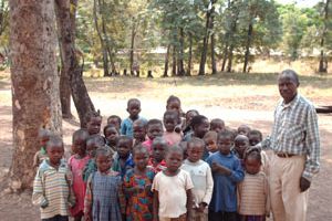 Un groupe d’enfants réunis sous les arbres avec un adulte, lors du voyage de 2008.