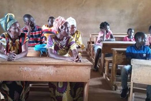Les tuteurs des cinq enfants réunis dans une salle de classe, assis aux pupitres.