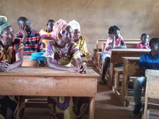 Les tuteurs des cinq enfants réunis dans une salle de classe, assis aux pupitres.