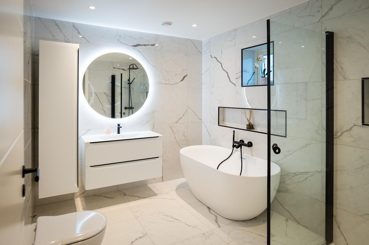 Moderne bad med hvite marmorfliser og sorte detaljer