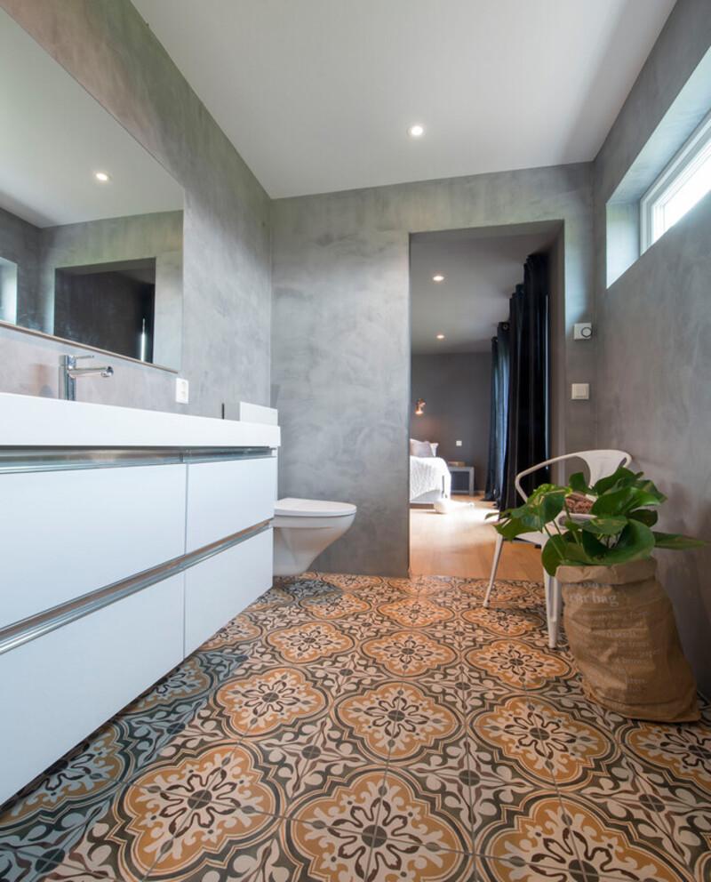Foreldresoverommet har eget bad – her er stilen helt annerledes, med rustikke fliser og betonglook på veggene.