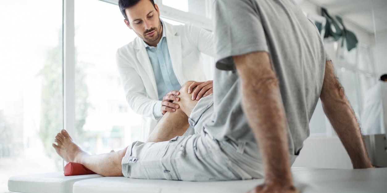 man laying while doctor holding his knee