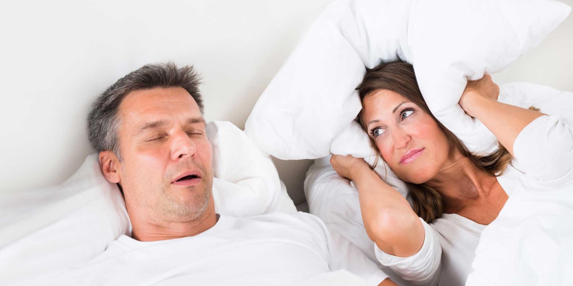 man snoring and woman covering her ears 