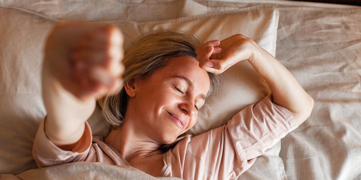 woman laying in bed strecthing smiling