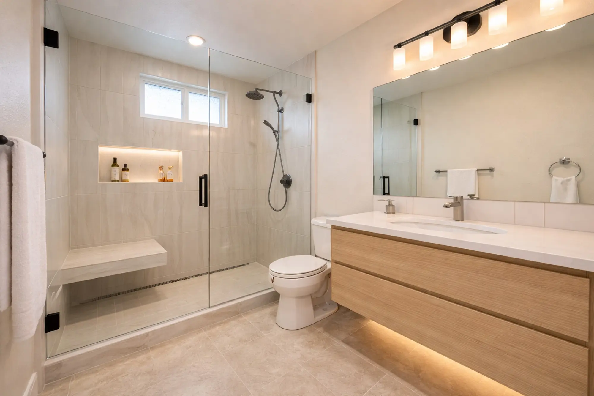 Beige tile shower with black fixtures and a white oak floating vanity ada bathroom remodel done by western renovations