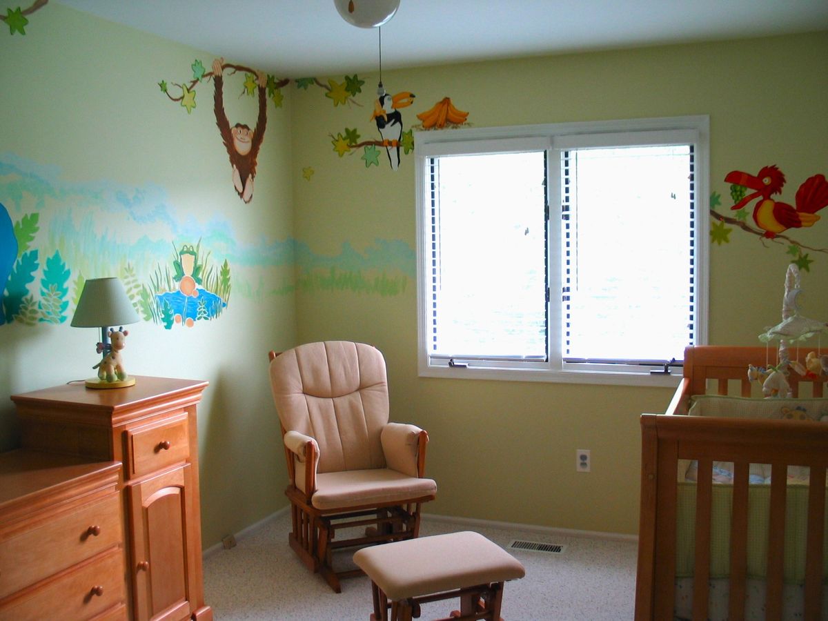 Children's room with a hand-painted jungle mural on the walls — armchair and crib by the window