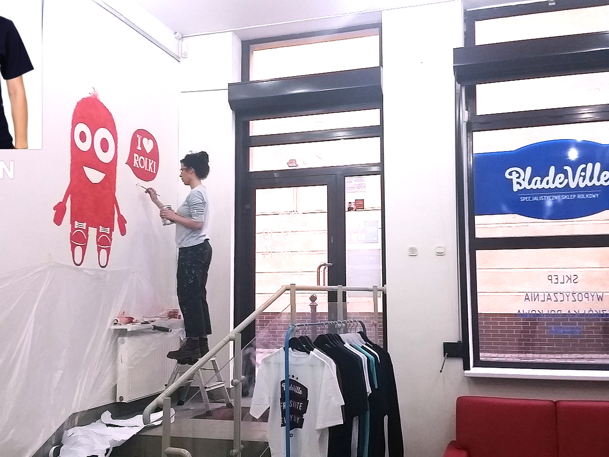 An artist is painting a mural a logo on the wall in a bladeroller store, in Warsaw.