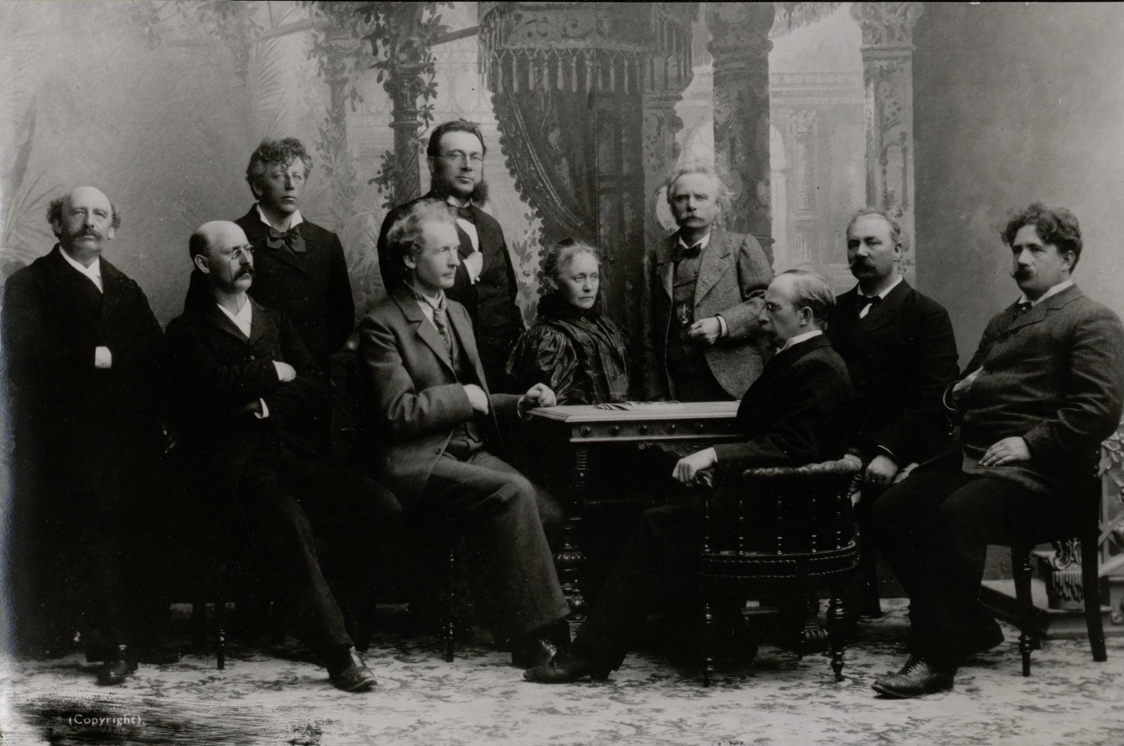 Sort-hvitt foto av en gruppe mennesker. Komponistene Agathe Backer Grøndahl og Edvard Grieg i midten.