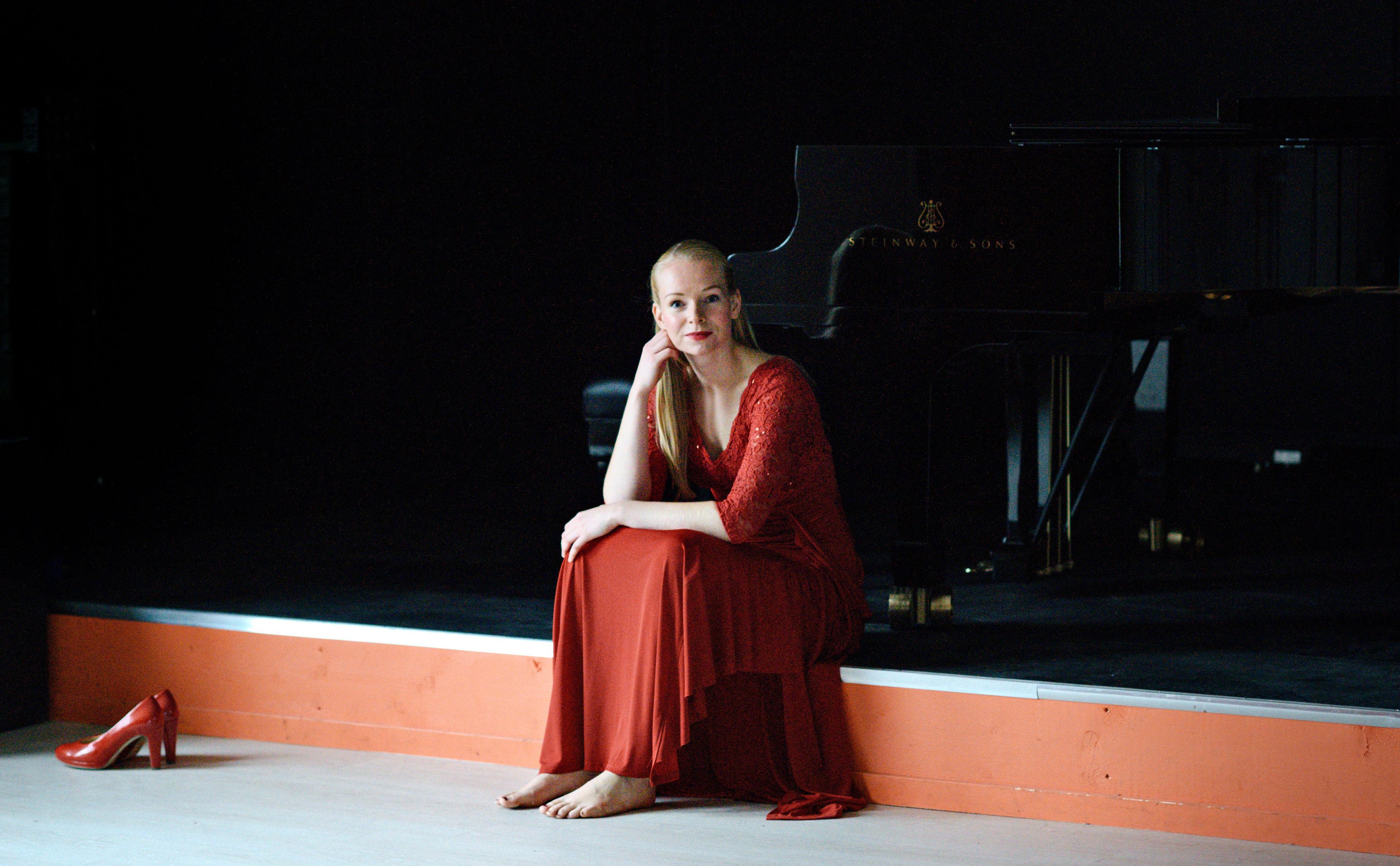 Et bilde av pianisten Ellisiv Tandberg, sittende på en scene i en rød kjole