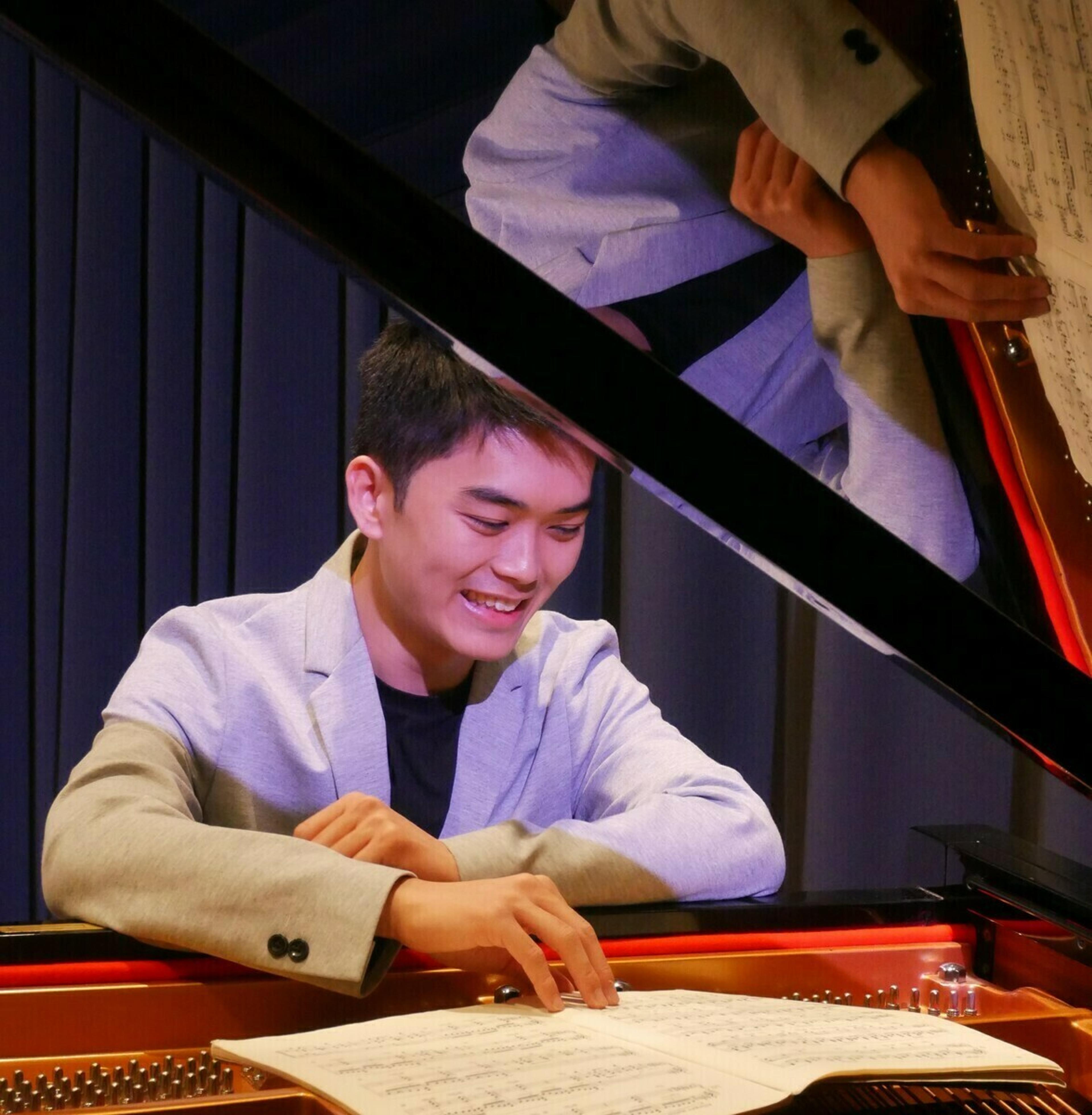 En mannlig pianist sitter ved et flygel mens han leser noter