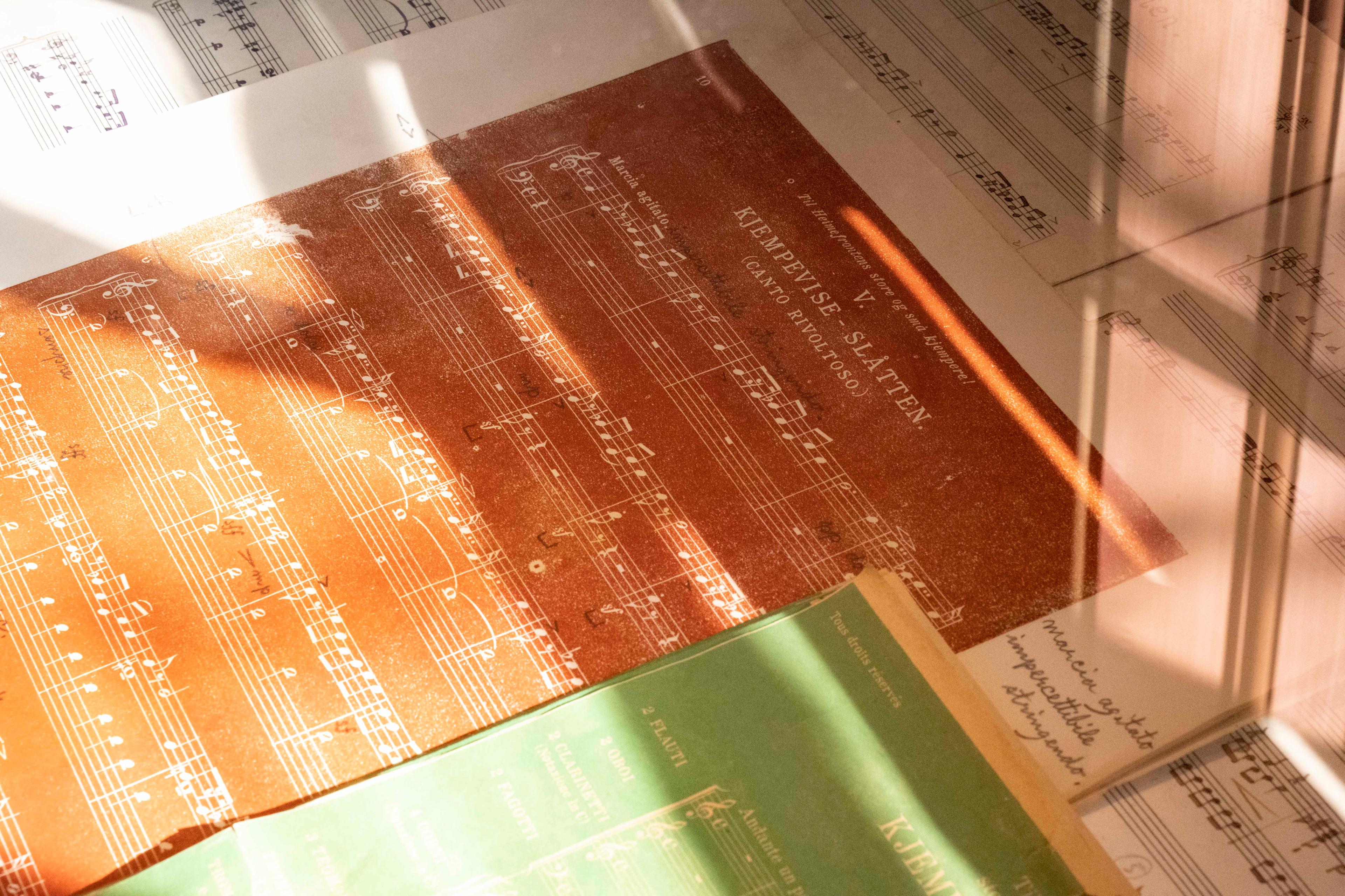 Colorful manuscripts of music pieces by Harald Sæverud are laying on a table.