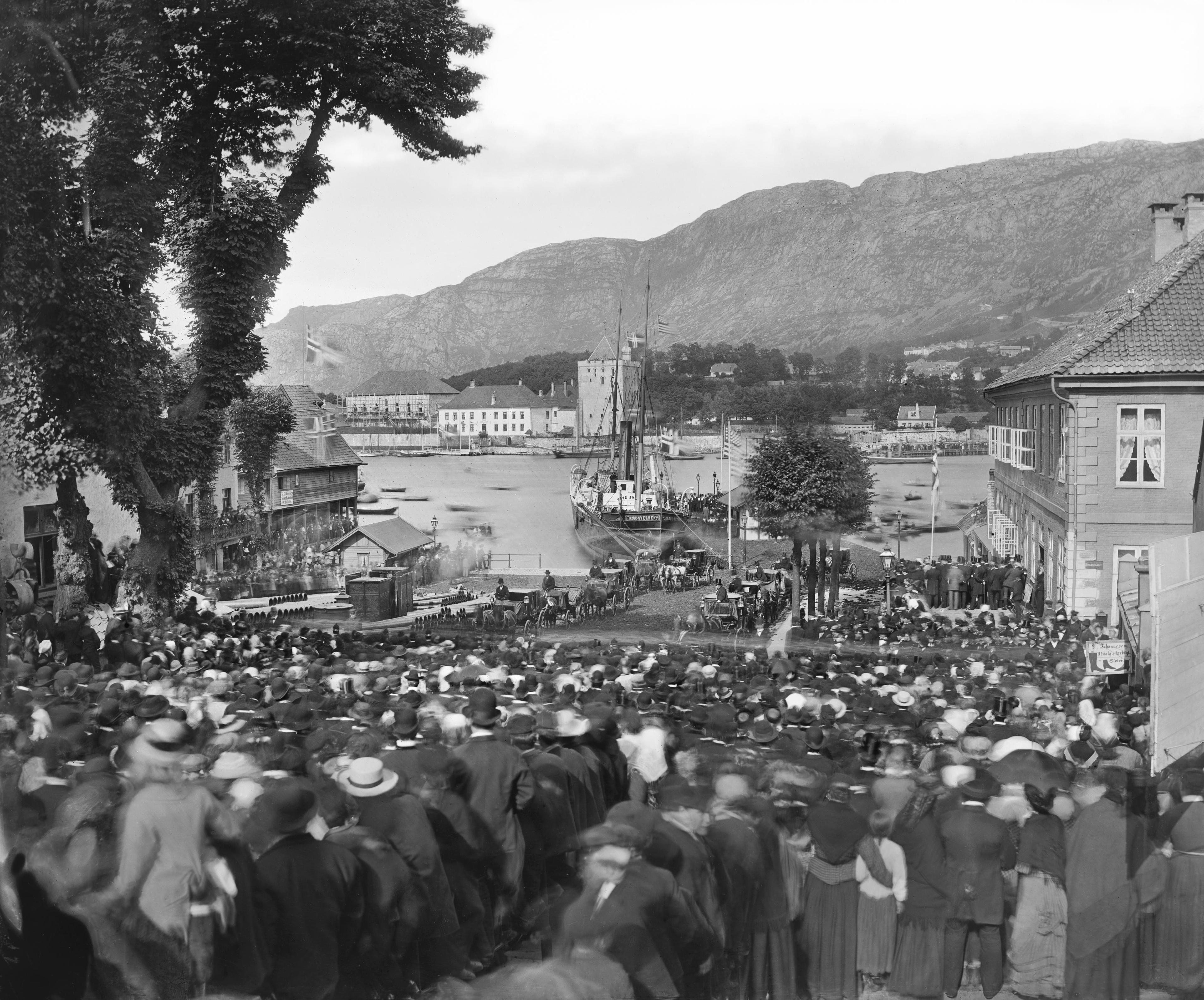 Fotografi fra Ole Bulls begravelse som viser utsikt ned mot kaien hvor kisten kommer i land via båt og en stor folkemengde som venter på å delta i folkeprosesjonen.